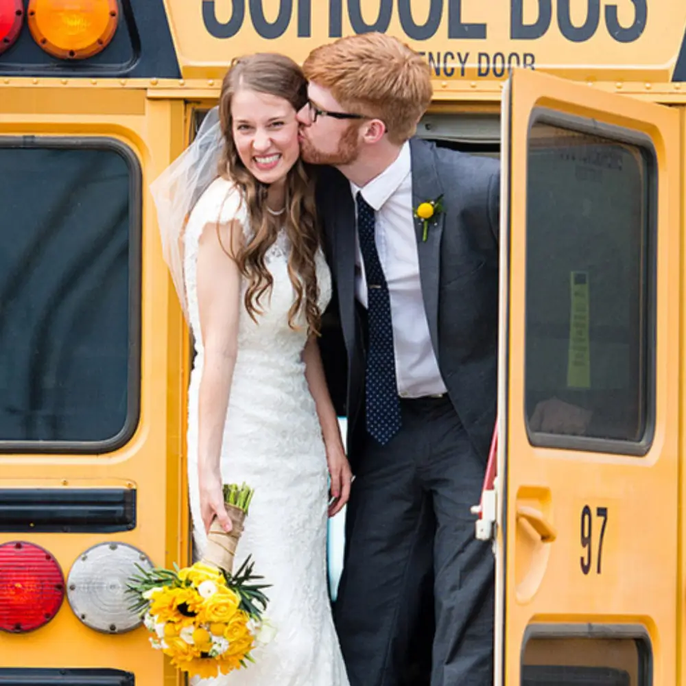 a man kissing a woman in front of a school bus